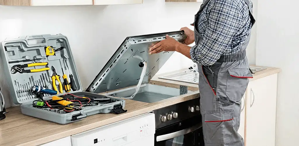 Handyman repairing a cooktop and checking wiring connections in Peoria, IL