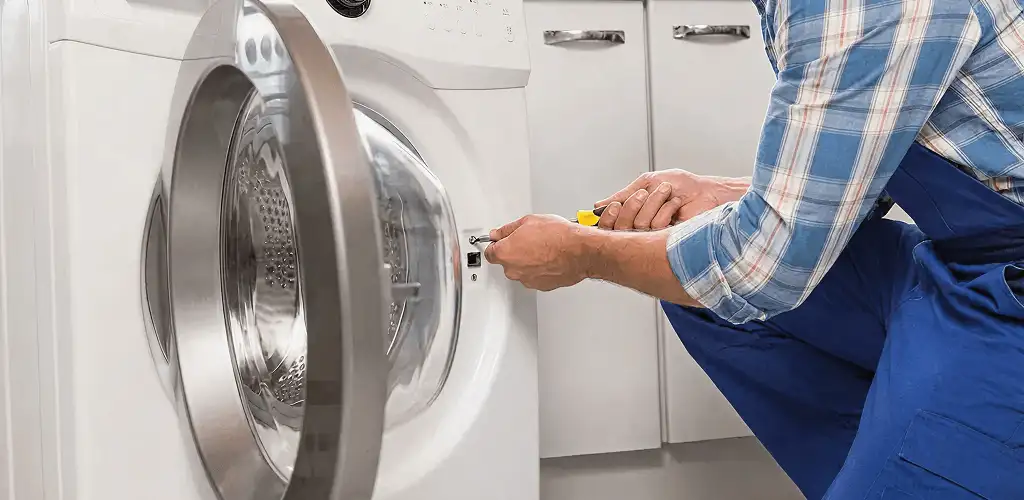 Handyman repairing a clothes dryer and checking electrical connections in Peoria, IL