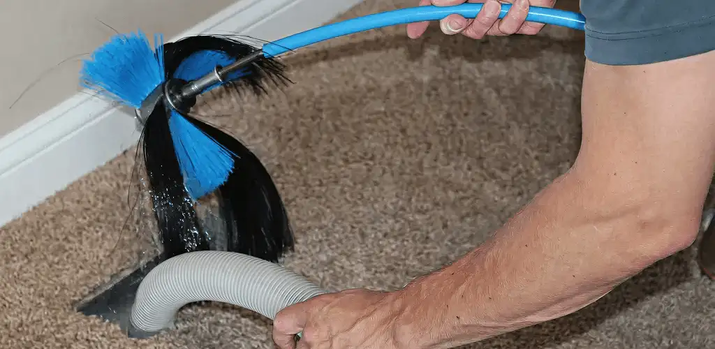 Dryer vent cleaning technician brushing lint from a vent line in Peoria, IL