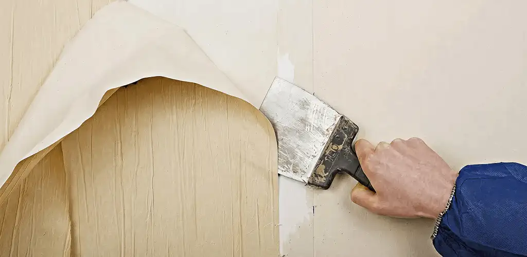 Handyman removing wallpaper with a scraper for wall preparation in Peoria, IL