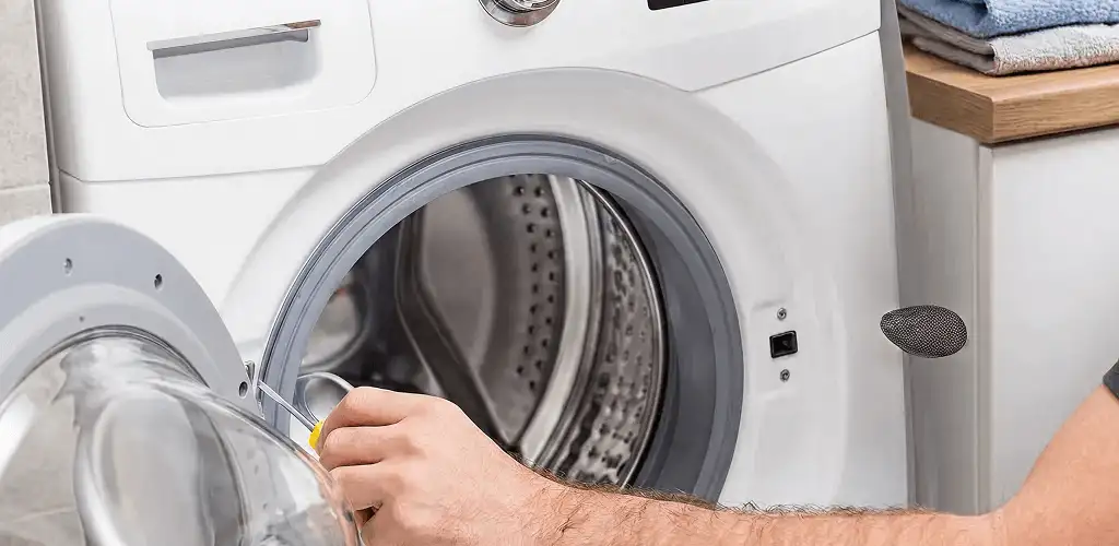 Handyman repairing a front-load washing machine and inspecting the drum in Peoria, IL