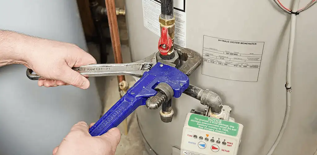 Water heater repair technician tightening the shutoff valve and supply line in Peoria, IL
